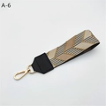 Detail of the wide woven strap with geometric pattern and gold swivel snap hooks - Khaki Arrow With Black Faux Leather (A-6)