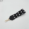 Close-up of a black and white polka dot wrist strap with a premium gold metal lobster clasp - Black Polka Dot With Black Faux Leather (A-7)