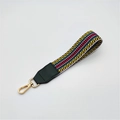 Detail of multi-color woven strap with geometric patterns and golden metal snap hook - Silver Clasp / Yellow Green Stripe + Green Leather