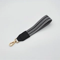 Detail of woven black and white handbag strap with golden lobster clasp and leather trim - Black