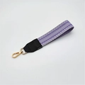 Close-up of a woven wristlet strap with purple and white geometric waves and gold lobster clasp - Silver Clasp / Light Purple + Black Leather