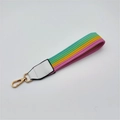 Macro shot of colorful rainbow striped braided wrist strap with gold metal clasp hook - Rainbow with White Leather
