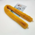 Detail of fluffy mustard yellow faux fur bag strap with gold lobster clasps on white background - Yellow