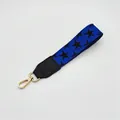 Détail de la dragonne bleu roi aux motifs d'étoiles noires et mousqueton doré brillant - Fermoir en Argent / N°12 Étoile Bleue