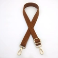 Close-up of caramel brown 2.5cm woven bag strap with geometric patterns and gold metal hooks - Brown