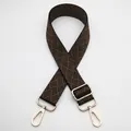 Macro detail of adjustable woven shoulder strap with gold hardware and geometric pattern - Silver Clasp / Black and Dark Khaki (No. 5) / [product Attributes] This Appears To Be A Widened Adjustable Replaceable Bag Strap. The Strap Features A Dark Brown And Black Woven Geometric Texture Presenting A Retro Ethnic Feel. Both Ends Are Equipped With Bright Gold Metal Lobster Buckles And Thickened Sliding Buckles Showcasing Exquisite Craftsmanship. [visual Presentation] The Image Is Taken Against A White Background Centered And Arranged In An "∞" Shape With Even Lighting And A Clear Contrast Between The Product And The Background. Image Quality Is [high] With Clear Details. Aesthetics Are [medium] Overall Score Is [7.5]. The Main Issue Is The Conventional White Background Image Presentation Lacking Brand Identity And Scene Appeal. [text Content] To_remove Contains A Separate Overlaid Chinese "5号" In The Upper Left Corner Which Is B2b Warehouse Identification Information And Should Be Removed; There Is No Other Text Information. [logistics Labels] None. [infringement Risk] Product Infringement: None; Background Infringement: None. Probability: [0.0]. [product Parameters] Includes One Widened Webbing Strap With Gold Hardware.