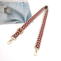 Detail of embroidered leaf pattern on adjustable beige canvas bag strap with gold metal buckles - Red