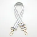 Close-up of white and silver striped woven bag strap with golden metal lobster clasps - White