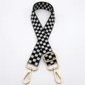 Close-up of black and white checkerboard bag strap with adjustable gold metal buckles - Black & White