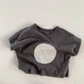 Detail eines dunkelgrauen Baumwoll-T-Shirts mit weißem runden Patch und lockerem Schnitt - 80cm / Grau