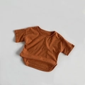 Detail of bamboo cotton fabric texture and curved hem on a rust red kids t-shirt - Orange