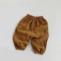Detail der atmungsaktiven Baumwollstruktur auf braunen Sommerhosen für Kinder - Ingwergelb