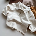 Detail eines Kinder-Poloshirts mit cremeweißem Baumwollstoff und geknöpftem Kragen - 80cm / Beige Aprikose