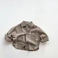 Dettaglio di una camicia di cotone per bambini con strisce marroni e taschino classico - 80cm / Cachi