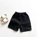 Detail view of black kids cotton shorts with elastic waistband and side pockets - Black / 80cm