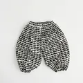 Dettaglio dei pantaloni harem per bambini in misto lino con motivo a onde bianco e nero - Beige Nero / 80cm