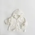 Detailed macro view of lightweight cotton kid's hooded jacket with wooden buttons and pockets - Beige / 80cm