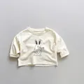 Dettaglio maglietta a maniche lunghe per bambini color crema con grafica a forma di coniglio - 80cm / Albicocca Beige