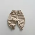 Close-up of beige knitted cargo sweatpants for kids featuring an elastic waist and side pocket - 80 / Milk Tea