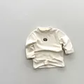 Détail du haut thermique enfant blanc cassé montrant le col montant et le patch brodé - 80cm / Abricot Beige