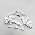 Detailansicht eines Kinder Langarm Polo-Shirts mit klassischem Kragen und Brustdruck - 80cm / Aprikose