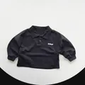 Detailansicht der gerippten Manschetten und des KWAY-Logos auf einem schwarzen Polo-Shirt - 80cm / Holzkohleschwarz