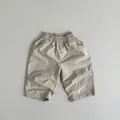 Detail view of children's cotton pants showing elastic waist and button stitching - Apricot / 80cm