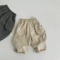 Detailed view of elastic waistband and large side flap pockets on cotton kids cargo pants - 80cm / Khaki
