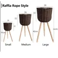 Three sizes of woven raffia plant stands with wooden tripod legs in a natural style - Raffia Dark Coffee Small Medium Large