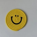 Yellow woven cotton cup coaster featuring a black smiley face and spiral braided texture - 15cm Golden Yellow Smiley