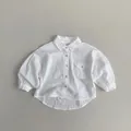 Dettaglio camicia bianca per bambini in cotone lino con tasca sul petto e bordo curvo - Bianco / 80cm