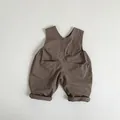 Detail van de bruine vintage katoenen babyoveralls met grote zakken en drie donkere knopen - 80cm / Bruin