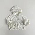 Dettaglio ravvicinato della giacca parasole leggera con cappuccio per bambini - 80cm / Beige Mandorla