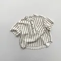 Detailed view of striped cotton shirt featuring wooden buttons and a front pocket - Apricot Stripe / 80cm