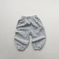 Dettaglio dei pantaloni a scacchi per bambini con vita alta ed elastico alle caviglie - 80cm / Quadri Neri e Bianchi