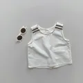 Detail der weißen Leinen-Kinderweste mit braun gestreiften Schultern und quadratischer Tasche - 80cm / Natürlicher Hanf