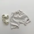 Detail of light beige double-layer cotton gauze kid shorts with elastic waist and letter patch - Beige / 80cm