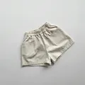 Detail of kids beige cotton shorts featuring elastic waistband and square patch pockets - 80cm / Milky Apricot