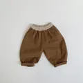 Detail of dark brown kids trousers with elastic light beige waistband and cuffed hems - Caramel color / 80cm