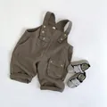 Detalle en plano de los petos de algodón marrón para niños y zapatillas de lona a rayas - Marrón / 80cm