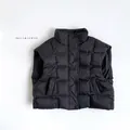 Detail view of black quilted down vest featuring a stand collar and snap button closure - Black / 80cm
