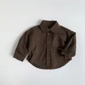 Detail view of dark brown cotton kids shirt featuring double pockets and embroidery - 80cm / Brown