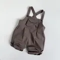 Detail of dark brown cotton kids overalls with functional front pocket and cross straps - Khaki