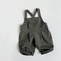 Detail of olive green cotton overalls featuring front pocket and buttoned rolled cuffs - Dark Green