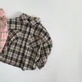 Detail of kids brown plaid flannel shirt showing lapel collar and front flap pockets - Black Plaid / 80cm