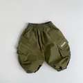 Gros plan détaillé d'un pantalon cargo enfant vert olive avec taille élastique et poche - Vert Herbe / 80cm