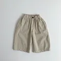 Detailed shot of elastic waist with black buttons on kids cotton trousers in khaki - Light Khaki / 80cm