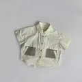 Detail van een crème shirt met korte mouwen, olijfgroene zakken en knopen - 80cm / Beige Abrikoos