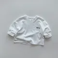 Dettaglio maglietta bianca a maniche lunghe per bambini in cotone con stampa Maroon sul petto - 80cm / Bianco