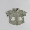 Detail van een olijfgroen katoenen shirt voor jongens met contrasterende witte zakken - 80cm / Lichtgroen